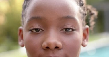 Portre yakın mutlu Afrikalı Amerikalı kız bahçede gülümsüyor, yavaş montajda. Mutluluk, rahatlama ve refah, değişmemiş..