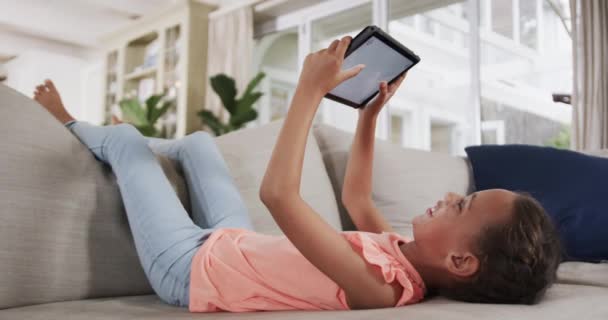 Szczęśliwa Dwurasowa Dziewczyna Leżąca Kanapie Używająca Tabletu Domu Zwolniony Ruch — Wideo stockowe