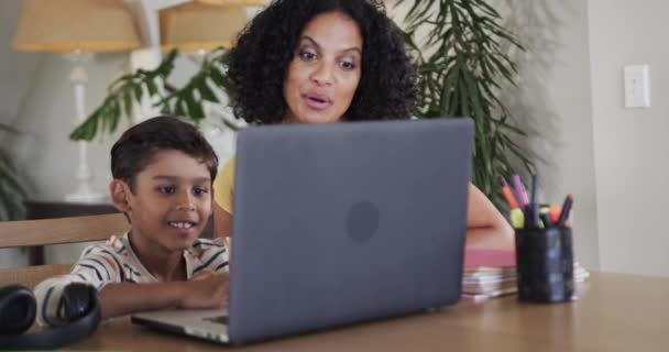 テーブルでラップトップを使用してオンライン学習する母親を持つBiracialの少年 スローモーション コミュニケーション オンライン学習 子供時代と家庭生活 変わらない — ストック動画