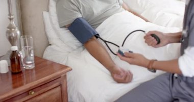 Farklı erkek doktorlar, yaşlı erkek hastaların kan basıncını evde yavaş çekimde ölçüyor. Sağlık hizmetleri, kontrol, ev ziyareti, sağlık hizmetleri, refah ve yaşlı yaşam tarzı, değişmemiş..