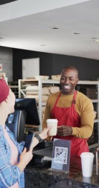 Kahvesini yavaş çekimde sallayan çeşitli işçi ve müşterilerin dikey videosu. İş, fırın, iş ve satış, değiştirilmemiş.