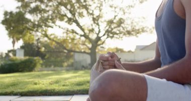 Güneşli bahçede yoga meditasyonu yapan odaklanmış çift ırklı bir adam, yavaş çekim. Yaz, refah, zindelik ve sağlıklı yaşam tarzı, değişmedi..