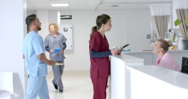 Muhtelif doktorlar hastanede resepsiyonistle konuşuyor, ağır çekimde. Hastane, takım çalışması, iletişim, tıp, sağlık ve iş, değiştirilmemiş.