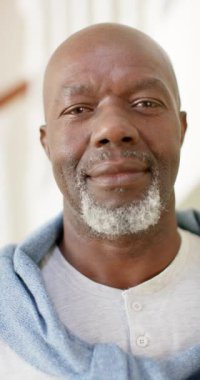 Memleketteki mutlu Afrika kökenli Amerikalı adamın portresinin dikey videosu. Ağır çekimde. Emeklilik, ev hayatı ve yaşlı yaşam tarzı değişmedi..