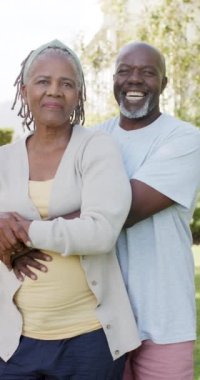Mutlu Afrika kökenli Amerikalı çiftlerin güneşli doğayla kucaklaştığı dikey video, yavaş çekim. Emeklilik, ev hayatı ve yaşlı yaşam tarzı değişmedi..