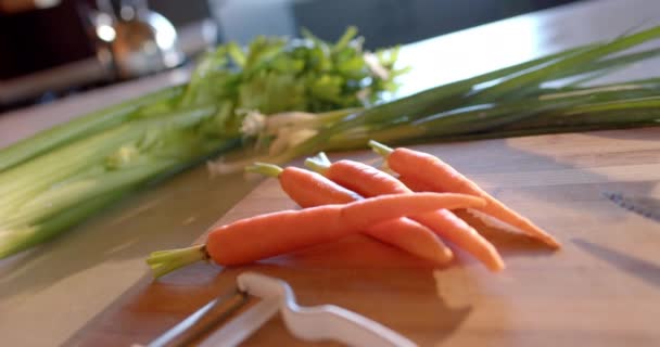 日当たりの良いキッチンでカウンターの上に有機野菜やピーラー スローモーション バランスの取れた食事と健康的な生活 — ストック動画