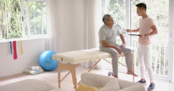 Diverso Fisioterapeuta Masculino Con Tableta Examina Paciente Masculino Mayor Cámara — Vídeo de stock