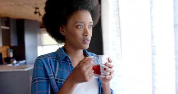 非洲裔美国妇女在阳光灿烂的厨房喝茶 动作缓慢 生活方式和家庭生活 — 图库视频影像