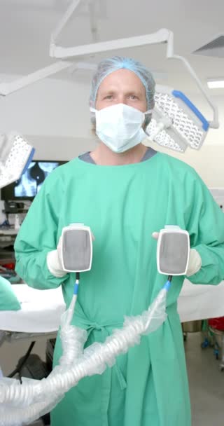 Verticale Video Van Portret Van Blanke Mannelijke Chirurg Met Defibrillator — Stockvideo