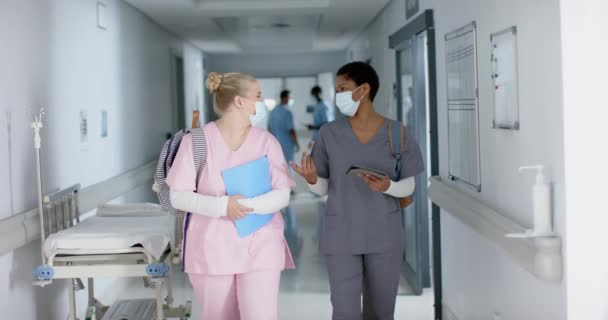 Szczęśliwa Zróżnicowana Lekarka Maskach Mówiąca Chodząca Korytarzem Zwolniona Szpital Praca — Wideo stockowe