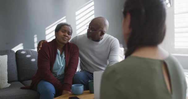 与坐在家里沙发上的非洲裔美国老年夫妇交谈的亚洲女性财务顾问 老年人的健康 支助和生活方式 — 图库视频影像