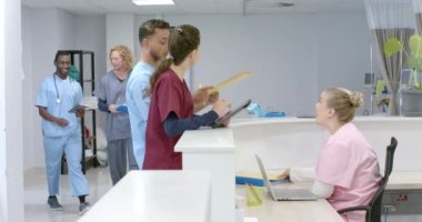 Muhtelif doktorlar hastanede resepsiyonistle konuşuyor, ağır çekimde. Hastane, takım çalışması, iletişim, tıp, sağlık ve iş, değiştirilmemiş.