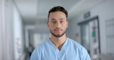Önlük giymiş, gülümseyen, ağır çekimde mutlu bir erkek doktorun portresi. Hastane, ilaç ve sağlık hizmetleri değiştirilmemiş..