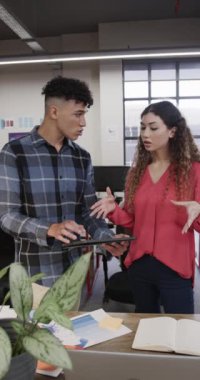 Gündelik ofiste tartışan iki farklı yaratıcı tasarımcının dikey videosu, yavaş çekim. Günlük ofis takım çalışması, iş, tasarım ve yaratıcı çalışma, değiştirilmemiş.