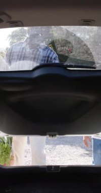 Afrika kökenli Amerikalı büyükbaba ve torununun alışveriş malzemelerini arabada ağır çekimde paketlediği dikey bir video. Alışveriş, aile, birliktelik, organik gıda, sağlıklı yaşam tarzı ve yerel iş, değişmemiş..