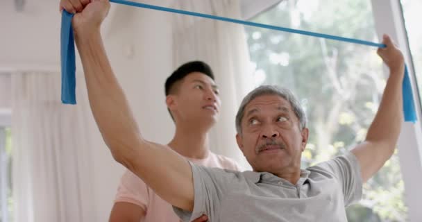 Různorodý Mužský Fyzioterapeut Poradenství Starší Mužský Pacient Pomocí Cvičební Pásmo — Stock video