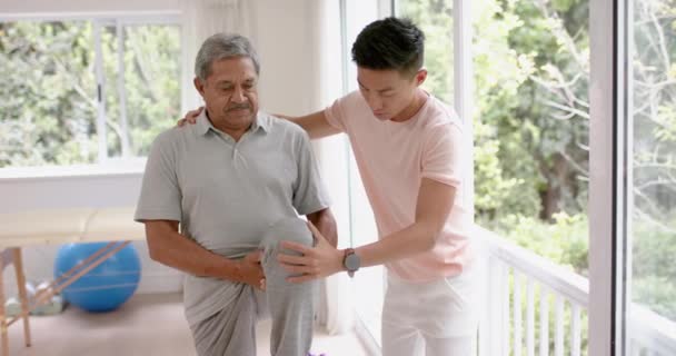 Diverse Männliche Physiotherapeuten Beraten Und Älteren Männlichen Patienten Stretching Zeitlupe — Stockvideo