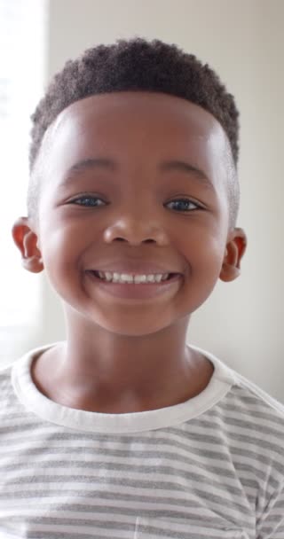 Vertikalt Videoportrett Lykkelig Amerikansk Gutt Som Smiler Hjemme Sakte Film – stockvideo