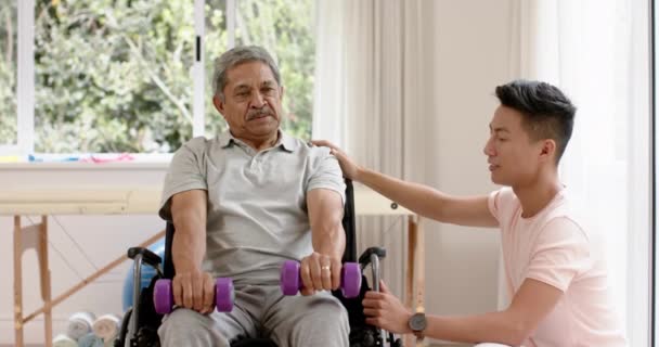 Türlü Erkek Fizyoterapist Tekerlekli Sandalyedeki Yaşlı Adam Yavaş Çekimde Dambıl — Stok video