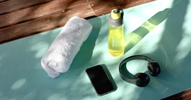 瓶装水 耳机和智能手机在瑜伽垫在木屋 慢动作 家庭生活 技术和体育设备 — 图库视频影像