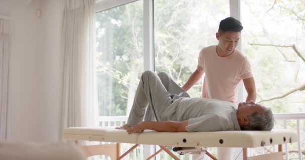 Různorodý Mužský Fyzioterapeut Poradit Starší Mužský Pacient Cvičení Gauči Zpomaleném — Stock video