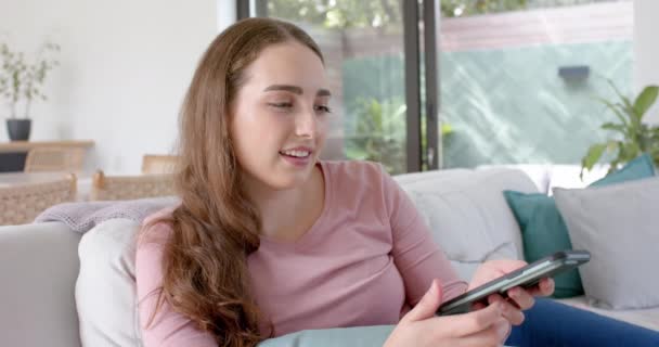 Onnellinen Valkoihoinen Nainen Makaa Sohvalla Puhuu Älypuhelimella Hidastettuna Kotielämä Teknologia — kuvapankkivideo