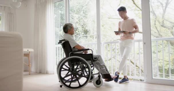 Διαφορετικός Άντρας Φυσιοθεραπευτής Συμβουλές Tablet Και Ηλικιωμένος Αναπηρική Καρέκλα Αργή — Αρχείο Βίντεο