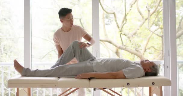 Divers Physiothérapeutes Masculins Conseillant Patient Masculin Aîné Faisant Exercice Sur — Video