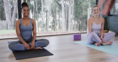 Yoga dersinde paspaslarda oturan mutlu kadınlar, ağır çekimde. Refah, zindelik, egzersiz ve sağlıklı yaşam tarzı, değişmemiş..