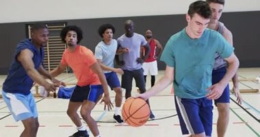 Çeşitli erkek basketbol oyuncuları kapalı sahada top sürüp atıyorlar, ağır çekimde. Spor, fitness, antrenman, rekabet ve takım aktiviteleri, değiştirilmemiş.