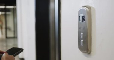 Ofiste akıllı telefon ve asansör kullanan melez bir iş kadınının orta bölümü, ağır çekim. Günlük ofis, iş, iletişim ve iş.