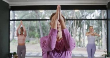 Yoga dersinde kadın antrenörle birlikte hasırlar üzerinde meditasyon yapan farklı kadınlar, ağır çekim. Refah, zindelik, egzersiz ve sağlıklı yaşam tarzı, değişmemiş..