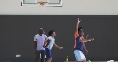 Kapalı sahada çeşitli erkek basketbol oyuncuları top blokluyor ve atıyorlar, ağır çekimde. Spor, fitness, antrenman, rekabet ve takım aktiviteleri, değiştirilmemiş.