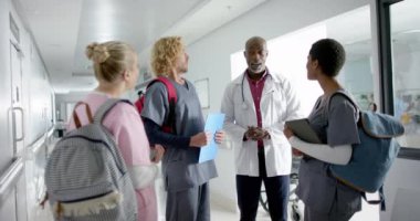 Çeşitli doktorlar hastanenin koridorunda ağır çekimde çalışmayı tartışıyor. Hastane, takım çalışması, ilaç, sağlık ve iş, değiştirilmemiş.