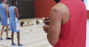 Çeşitli erkek basketbol takımları antrenman yapıyor ve iç sahada yavaş çekimde notlar alıyor. Spor, antrenman, fitness, taktik ve takım aktiviteleri, değiştirilmemiş.