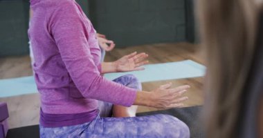 Yoga dersinde paspaslar üzerinde birlikte meditasyon yapan düşük odaklı kadınlar, yavaş çekim. Refah, zindelik, egzersiz ve sağlıklı yaşam tarzı, değişmemiş..