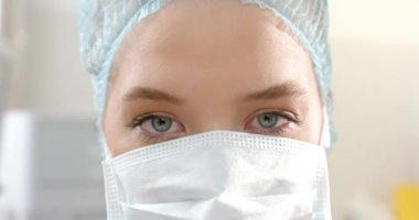 Kafkas kadın cerrahın portresi cerrahi başlık ve yüz maskesi takıyor, ağır çekimde. Hastane, ameliyat, ilaç, sağlık ve iş, değiştirilmemiş.