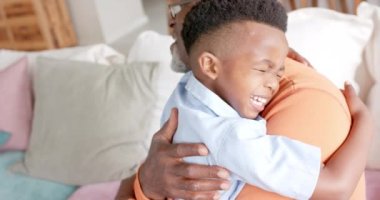 Mutlu Afrikalı Amerikalı torun ve büyükbaba evdeki kanepede kucaklaşıp gülümsüyor, ağır çekimde. Aile, yaşam tarzı, çocukluk, rahatlama ve aile hayatı, değişmemiş..