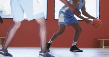 Çeşitli erkek basketbol oyuncuları kapalı sahada top sürüyor ve atış yapıyorlar, ağır çekimde. Spor, fitness, antrenman, rekabet ve takım aktiviteleri, değiştirilmemiş.