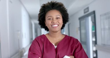 Koridorda önlük giyen mutlu Afro-Amerikan kadın doktor portresi, ağır çekimde. Hastane, ilaç, sağlık ve iş, değiştirilmemiş.