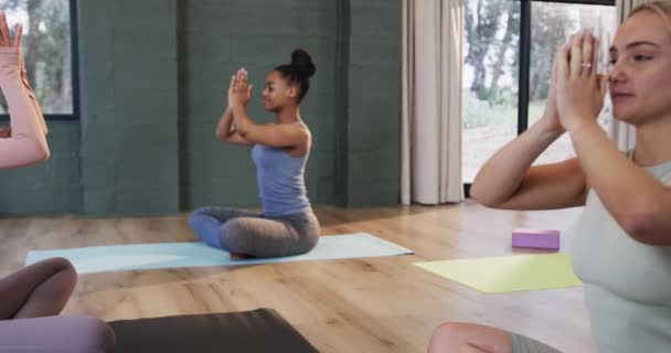 女性コーチとヨガクラスのマットで一緒に瞑想する多様な女性に焦点を当て スローモーション フィットネス 運動と健康的なライフスタイル 変更なし — ストック動画