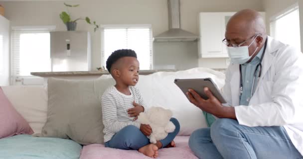 Senior Afroamericano Médico Masculino Mascarilla Usando Tableta Hablando Con Niño — Vídeo de stock