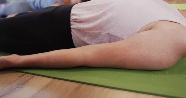 集中在瑜伽课上与女教练一起躺在垫子上 动作缓慢 运动和健康的生活方式 — 图库视频影像
