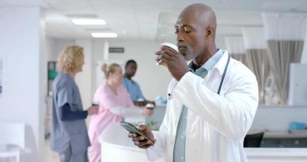 Happy African American Male Doctor Using Smartphone Drinking Coffee Hospital — Stock Video