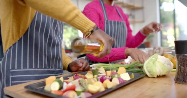 Afro Amerikan Çiftin Önlüklü Orta Kesimi Mutfakta Sebzelere Yağ Döküyor — Stok video