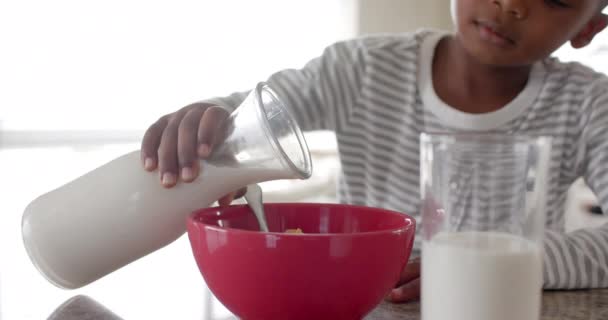 Afrykański Amerykański Chłopiec Jedzący Śniadanie Nalewając Mleko Płatki Kuchni Zwolniony — Wideo stockowe