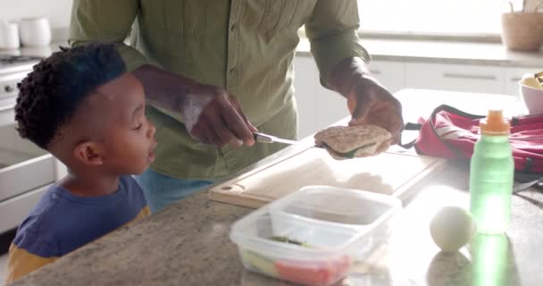 アフリカ系アメリカ人の祖父は 学校の前に台所で孫と一緒に昼食を作って スローモーション ライフスタイル 子供時代 一緒に ケアと家庭生活 変わらない — ストック動画