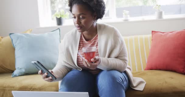 Зосереджена Афроамериканська Жінка Яка Працює Вдома Має Чай Використовуючи Смартфон — стокове відео
