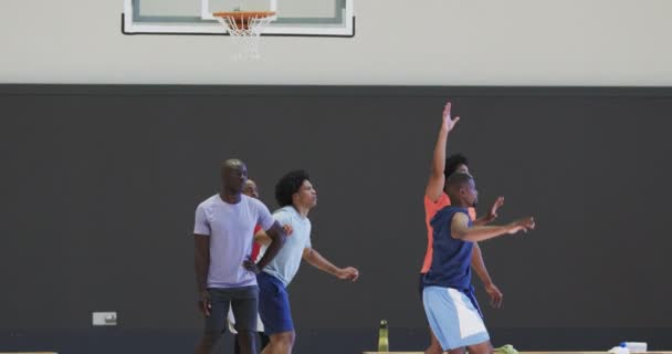 Zróżnicowane Męskie Koszykarze Blokowanie Strzelanie Piłkę Podczas Gry Boisku Kryty — Wideo stockowe