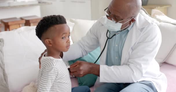 Ανώτερος Αφροαμερικανός Γιατρός Μάσκα Προσώπου Χρησιμοποιώντας Στηθοσκόπιο Ασθενή Αγόρι Αργή — Αρχείο Βίντεο